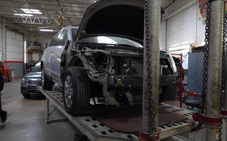 SUV on frame rack during collision repair at Modern Carriage Werks auto body shop